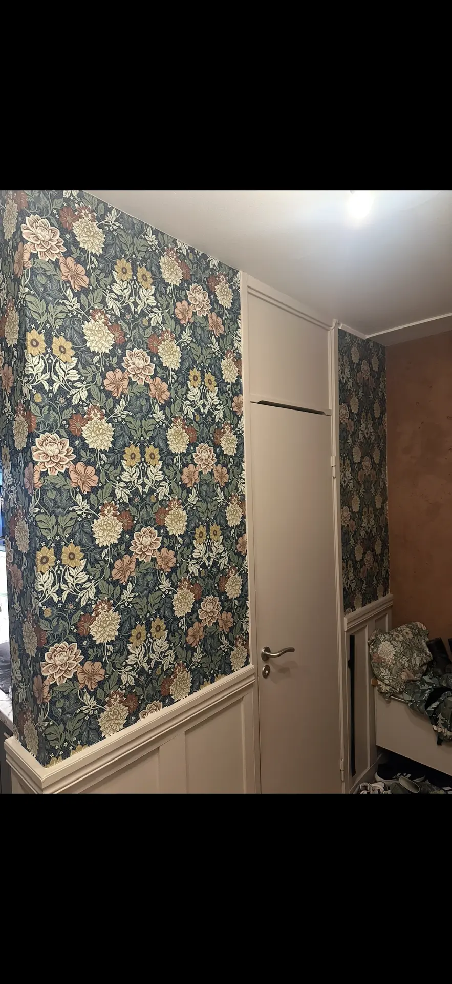 Hall med blommig tapet och vitmålad bröstpanel