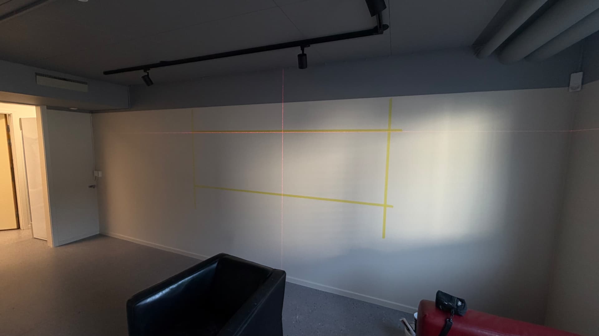 Vägg under målningsarbete med laser och maskeringstejp