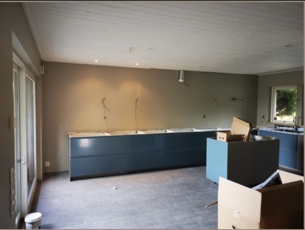 Kök under renovering med grönbeige väggar och blå köksluckor